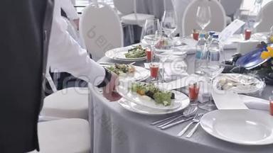 饮食服务服务员在婚礼或会议上把盘子和盘子放在客人的桌子上。